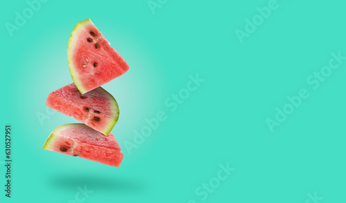 Slices of fresh juicy watermelon falling on turquoise background  space for text. Banner design