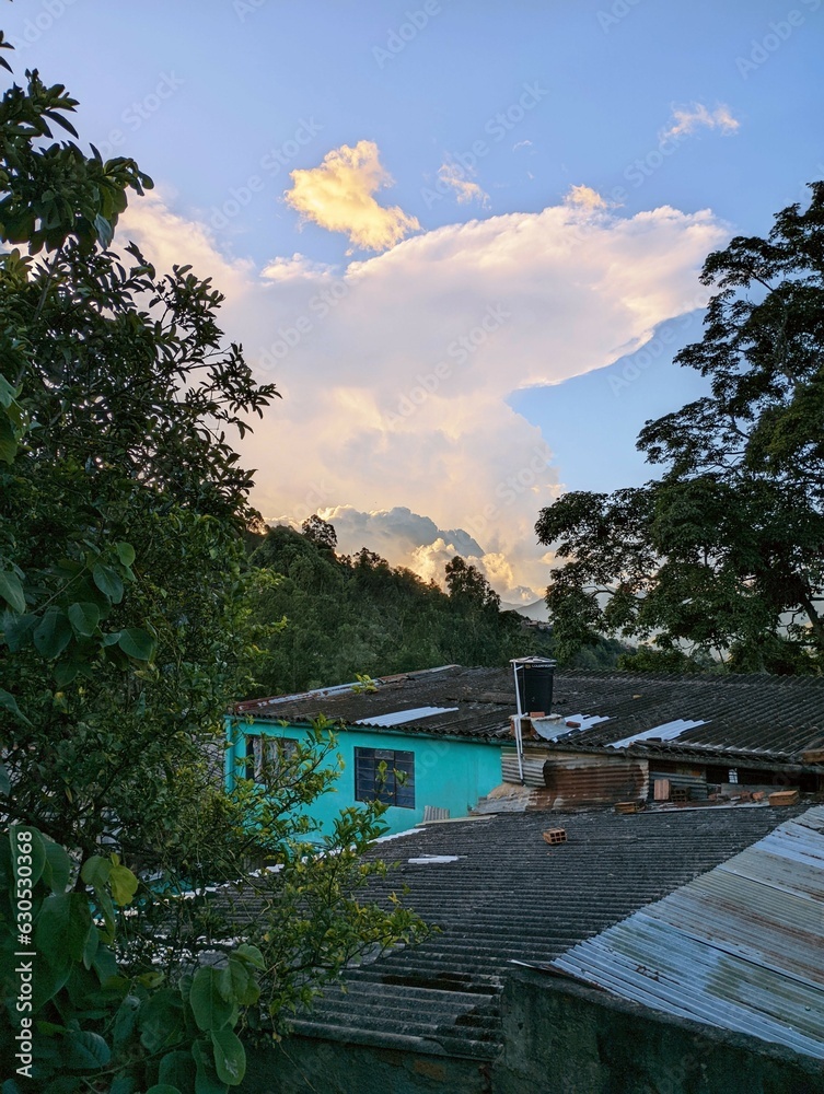 vista de un atardecer con un cielo azul y unas coloridas nubes naranja en una casa de campo