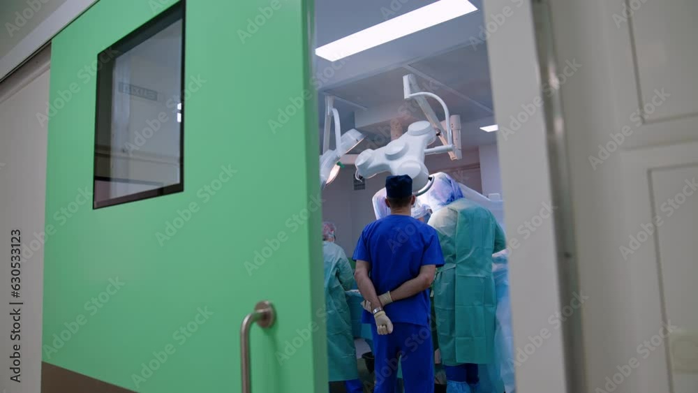 Slightly open door to a modern surgery room. Operation is in process in the operational theatre. Slightly open door to a modern surgery room. Operation is in process in the operational theatre.