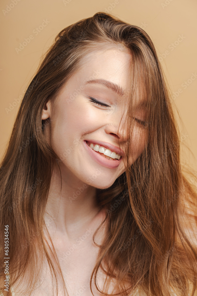 Portrait of beautiful woman with long hair with closed eyes smiling isolated on beige background Portrait of beautiful woman with long hair with closed eyes smiling isolated on beige background