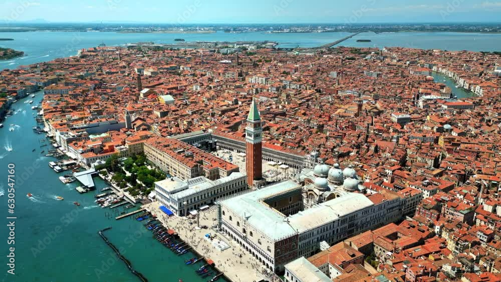 Aerial drone view of Venice, Italy. Water channels with multiple floating and moored boats, historical city centre with St Mark's Square and other old buildings and narrow streets