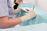 Female dermatologist removes birthmark for skin cancer prevention using a scalpel for the surgery on patient in clinic