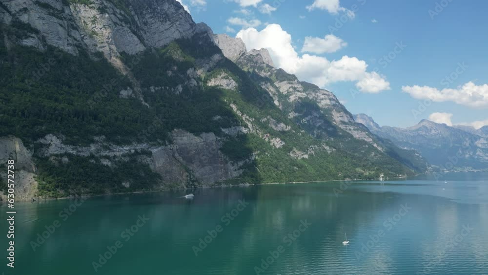 Turquoise waters of Walensee lake in Switzerland embraced with rocky Swiss Alps at shoreline