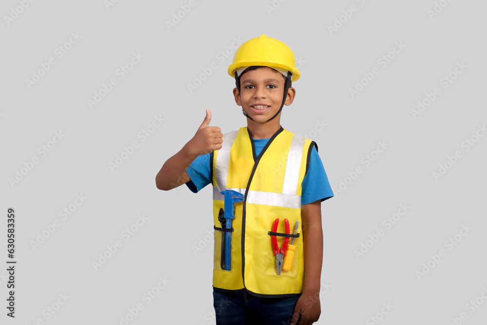 Future architect Indian Boy wearing yellow Safety jacket and helmet showing thumbs up, Concept little engineer 