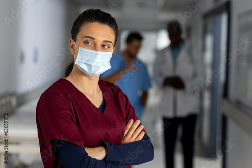 Caucasian female doctor wearing face mask in corridor at hospital