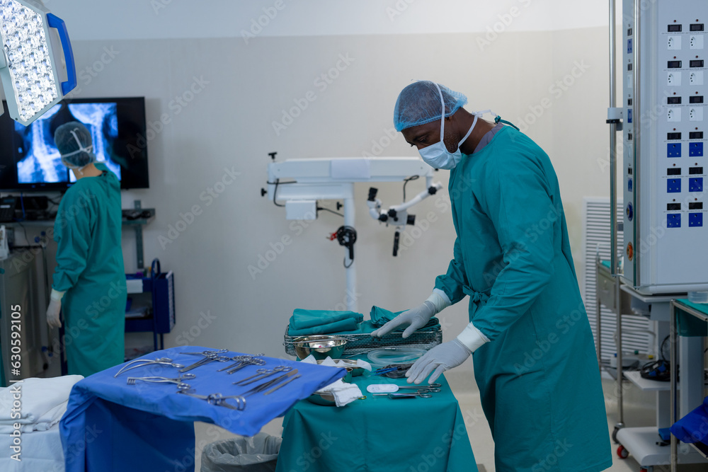 African american male surgeon preparing surgical instruments in operating theatre at hospital African american male surgeon preparing surgical instruments in operating theatre at hospital