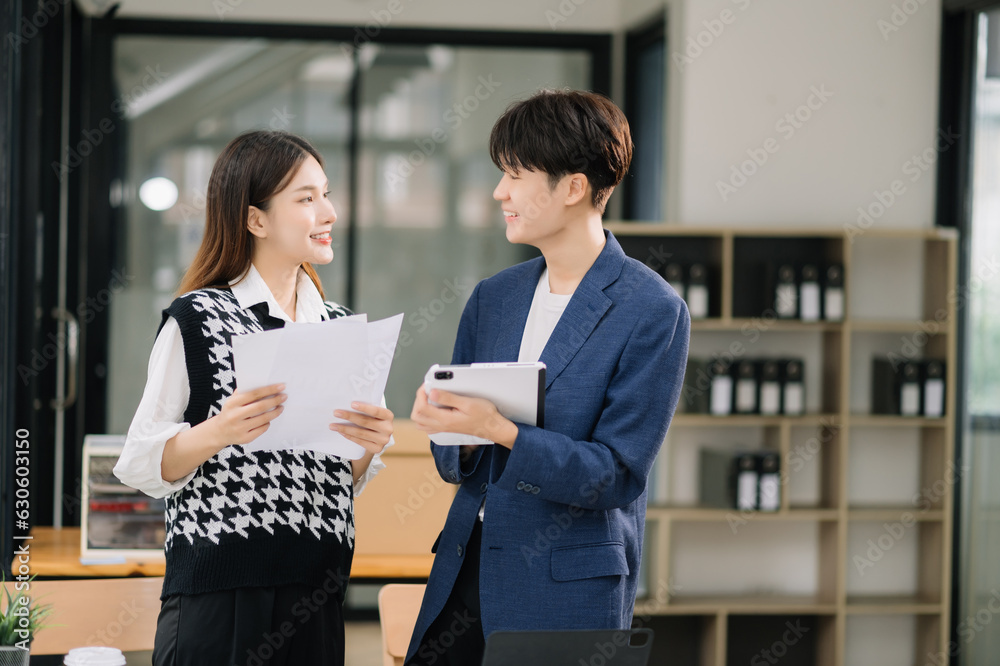 Two Asian business workers talking on the smartphone and using laptop at the modern office. Two Asian business workers talking on the smartphone and using laptop at the modern office.