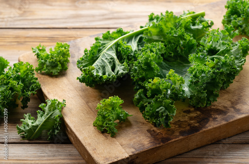 Cutting board and kale on wooden background. curly kale.