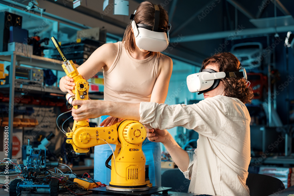 Young man and woman in VR glasses doing experiments in robotics in a laboratory
