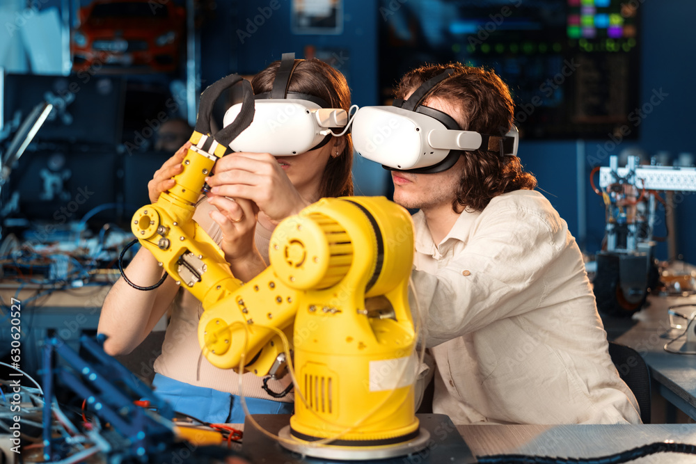 Young man and woman in VR glasses doing experiments in robotics in a laboratory
