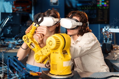 Obraz na płótnie Young man and woman in VR glasses doing experiments in robotics in a laboratory w salonie