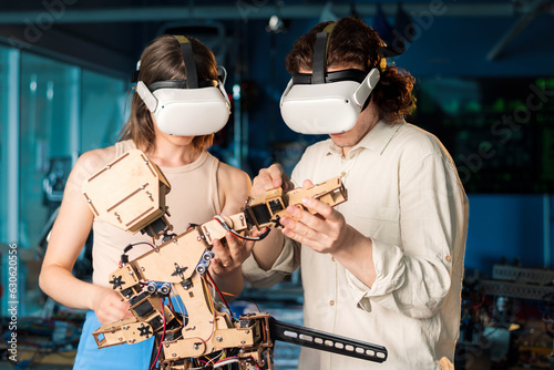 Young man and woman in VR glasses doing experiments in robotics in a laboratory © frimufilms