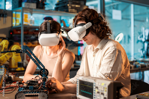 Obraz na płótnie Young man and woman in VR glasses doing experiments in robotics in a laboratory w salonie