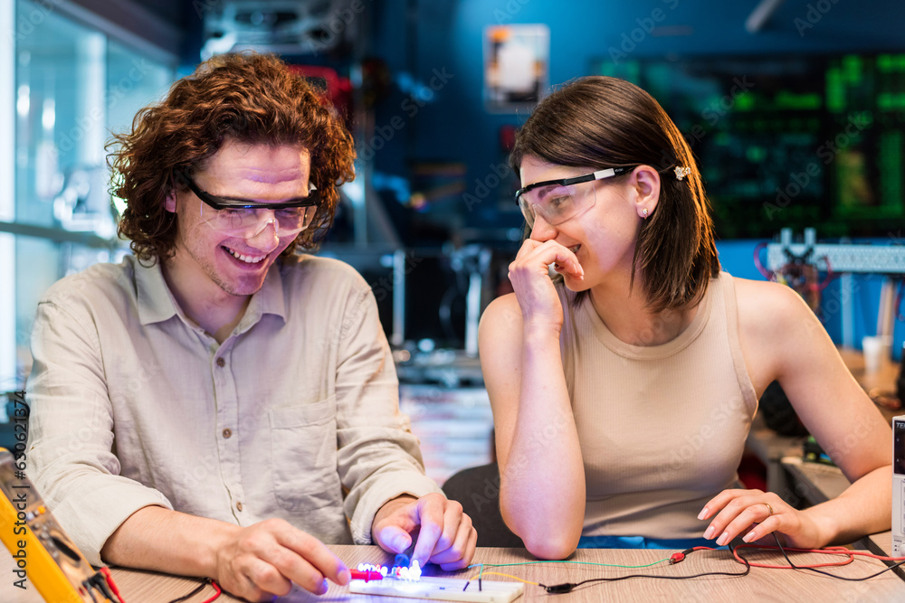 Fototapeta premium Young man and woman doing experiments with electricity in a laboratory