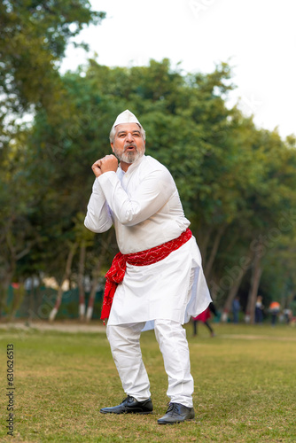 Indian senior man in traditional wear celebrating and giving dancing expression at garden. photo