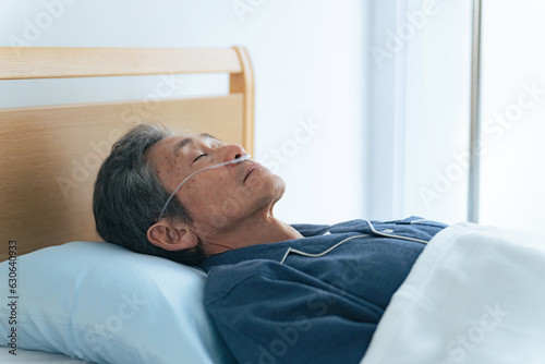 酸素チューブをつけてベッドに寝るシニア男性