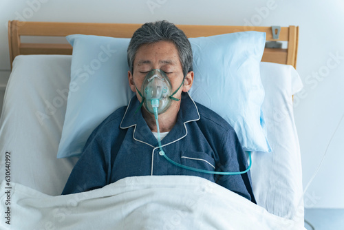酸素マスクをつけてベッドに寝るシニア男性 photo