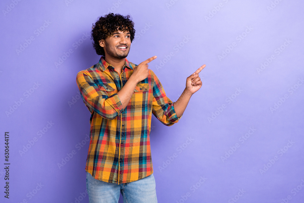 Photo of young man promoter student wear plaid shirt indicate fingers empty space looking advertisement isolated on purple color background Photo of young man promoter student wear plaid shirt indicate fingers empty space looking advertisement isolated on purple color background