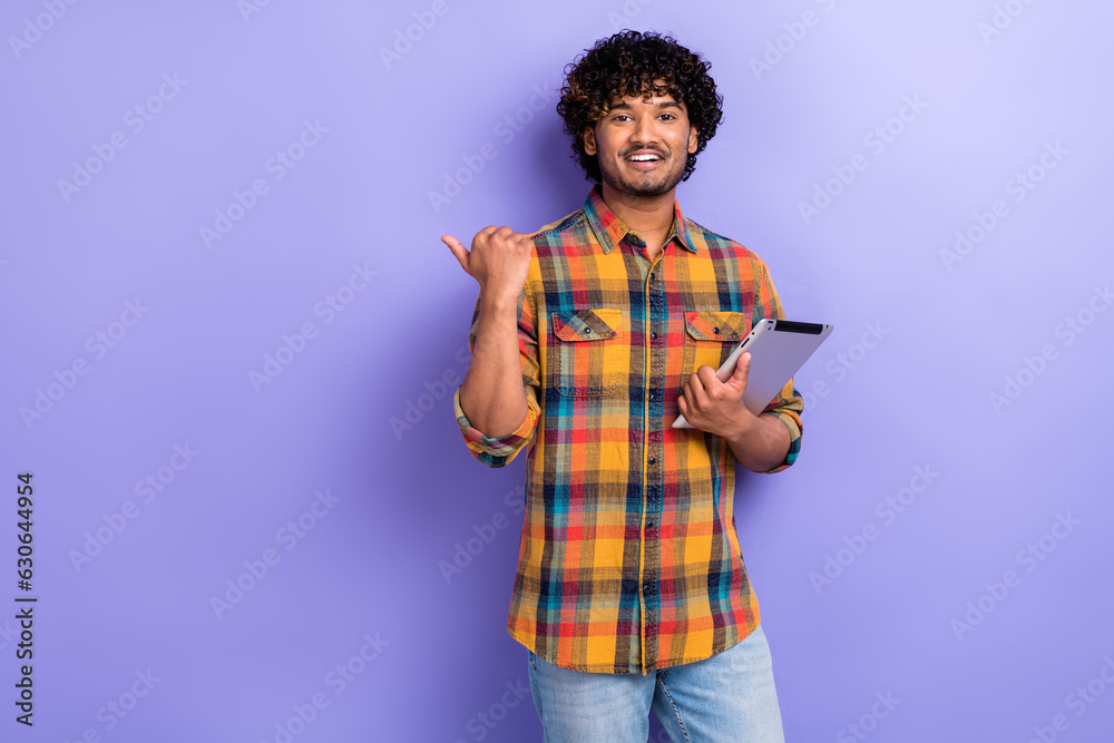 Photo of young man direct finger useful information advert for web interface users hold tablet device isolated on violet color background Photo of young man direct finger useful information advert for web interface users hold tablet device isolated on violet color background