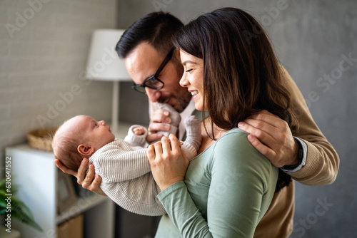 Proud mother and father smiling at their newborn baby daughter, son at home