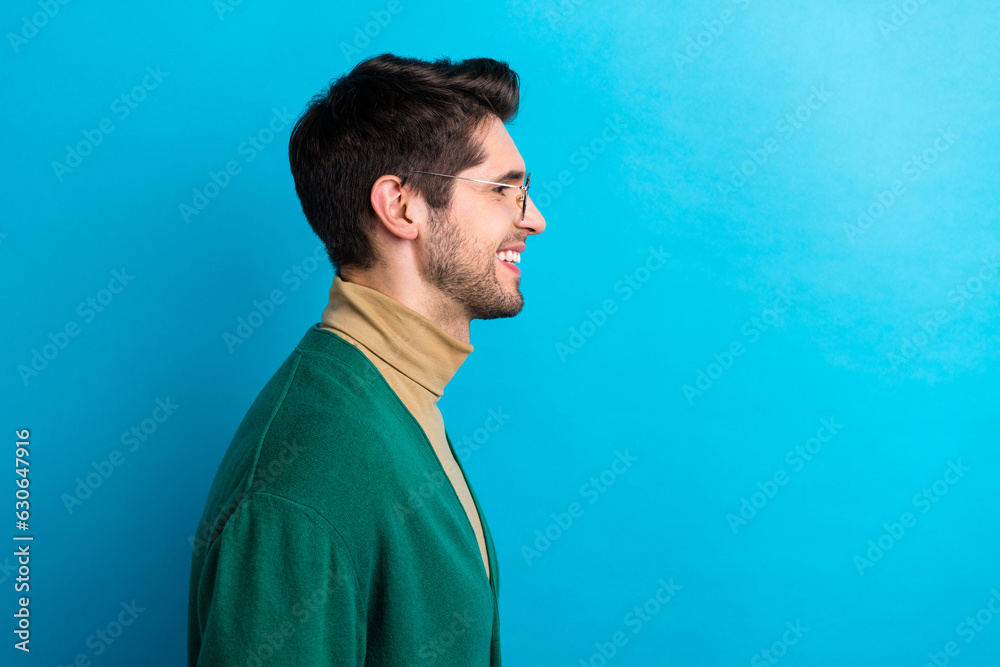 Profile photo of cheerful young man wear green cardigan beige turtleneck stylish goggles look empty space isolated on blue color background Profile photo of cheerful young man wear green cardigan beige turtleneck stylish goggles look empty space isolated on blue color background