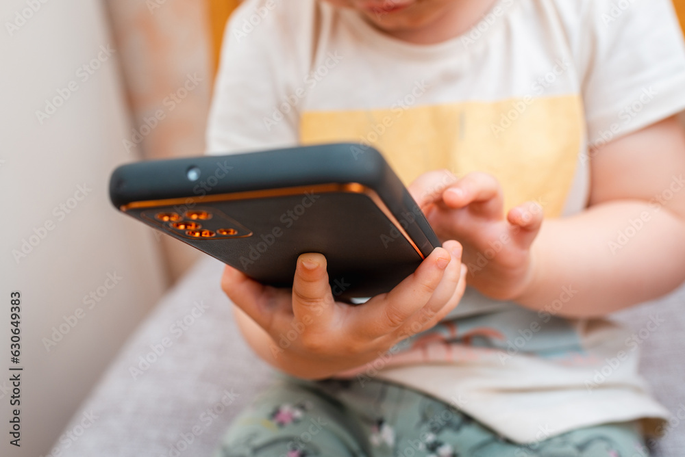 A baby girl,toddler, infant, adorable kid 1,2 years old sitting and using mobile phone,technology at home.Having fun indoors,development concept. A baby girl,toddler, infant, adorable kid 1,2 years old sitting and using mobile phone,technology at home.Having fun indoors,development concept.