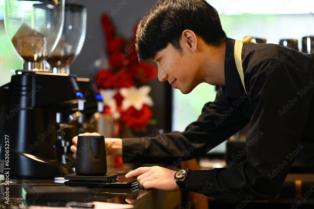 Smiling male barista preparing coffee for customer order in trendy coffee. Small business concept.
