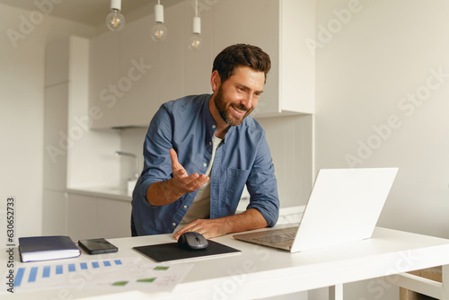 Male freelancer have a video conference from laptop during distance work from home kitchen