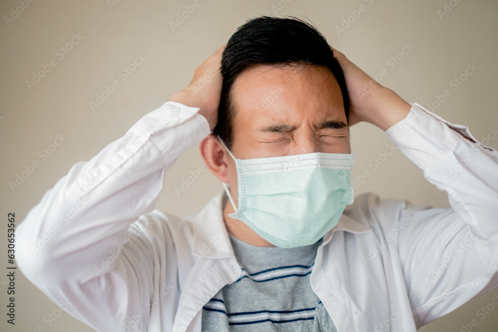 Upset and stressed young asian man in medical facial mask feel lonely distressed sick with covid-19. Corona virus, pandemic and quarantine stay at home concept. Upset and stressed young asian man in medical facial mask feel lonely distressed sick with covid-19. Corona virus, pandemic and quarantine stay at home concept.