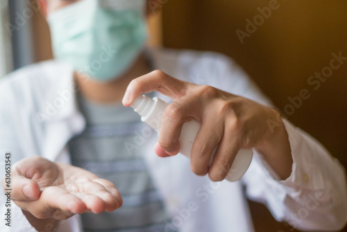 high angle view on unknow asian man applying spray alcohol product on hand disinfecting against virus or bacteria in COVID-19 situations at work or at home
