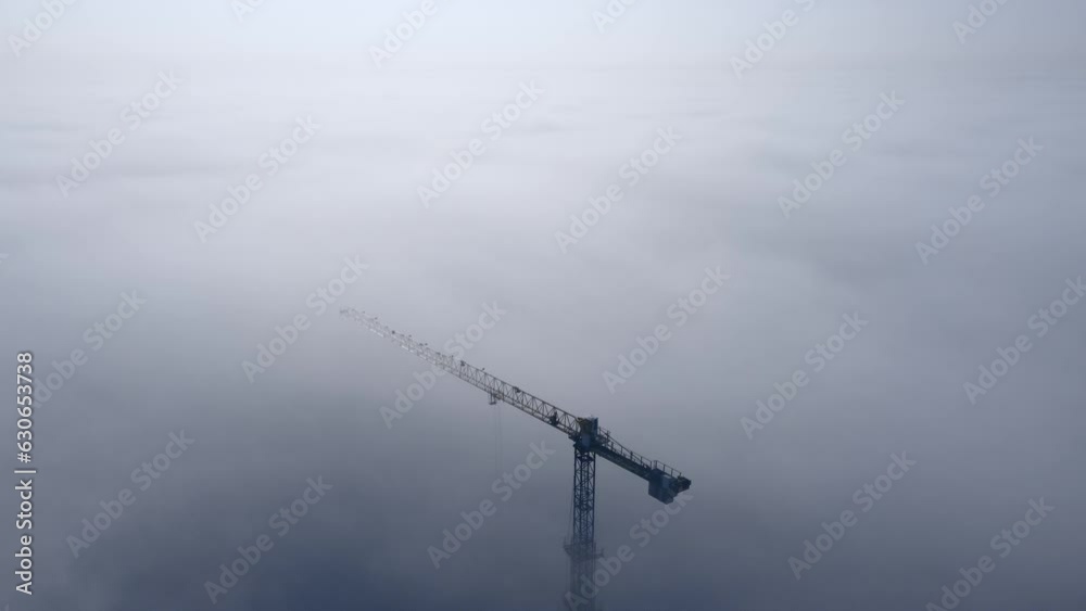 Drone flying over fog and clouds over construction. Construction crane and buildings in the fog. Industrial concept background. Drone flying over fog and clouds over construction. Construction crane and buildings in the fog. Industrial concept background.