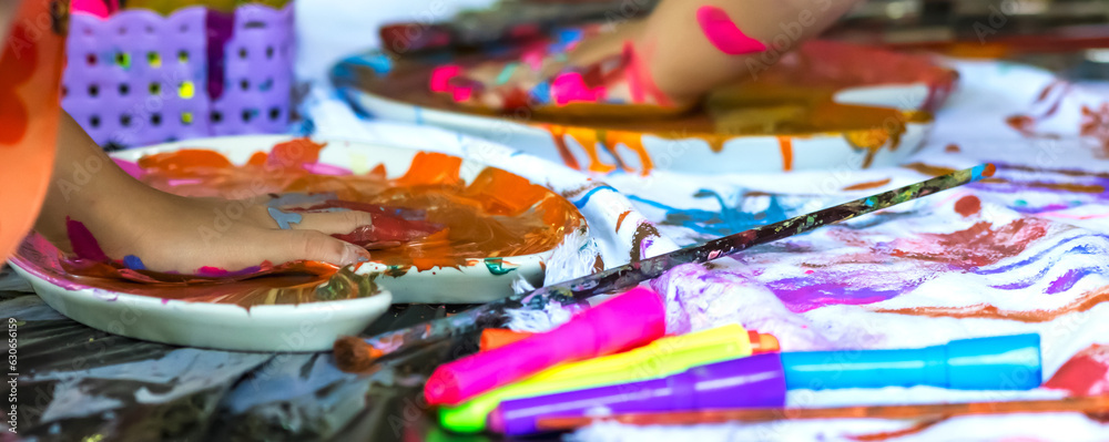 Kid putting hands in paint palette , dirty hands artist with colorful water color paint in art school, banner size
