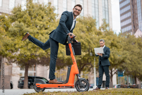 Crazy business, fast and easy. Funny excited business man on electric scooter on city street. Employee business man corporate lawyer in suit riding e-scooter. Business man in a suit scooter on meeting