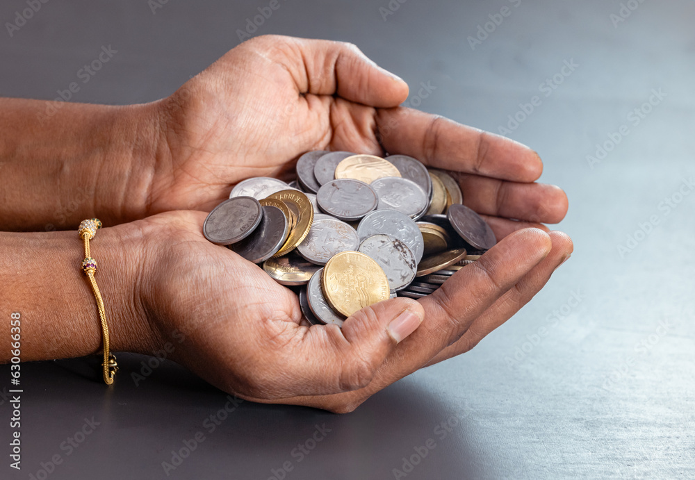 hand holding a large handful of Indian coins