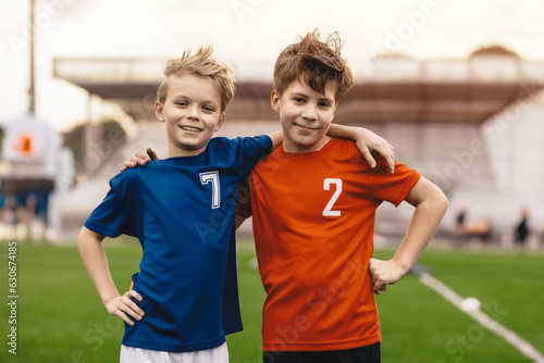 Children's Friendship in Sports Competition. Kids soccer players in school sports tournaments. Happy boys in football team smiling to the camera. Two school boys teammates in red and blue jersey shirt photo