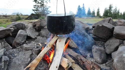 Bonfire campfire with pot cooking food on fire in mountains. Full HD video clip