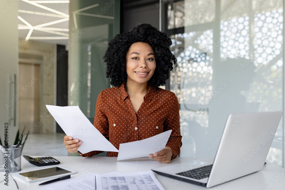 Portrait of successful satisfied and confident woman boss financier at workplace, african american smiling and looking at camera, businesswoman behind paperwork inside office working with papers. Portrait of successful satisfied and confident woman boss financier at workplace, african american smiling and looking at camera, businesswoman behind paperwork inside office working with papers.