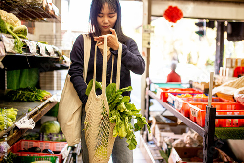 20-something Asian woman shopping buying groceries at a supermarket photo