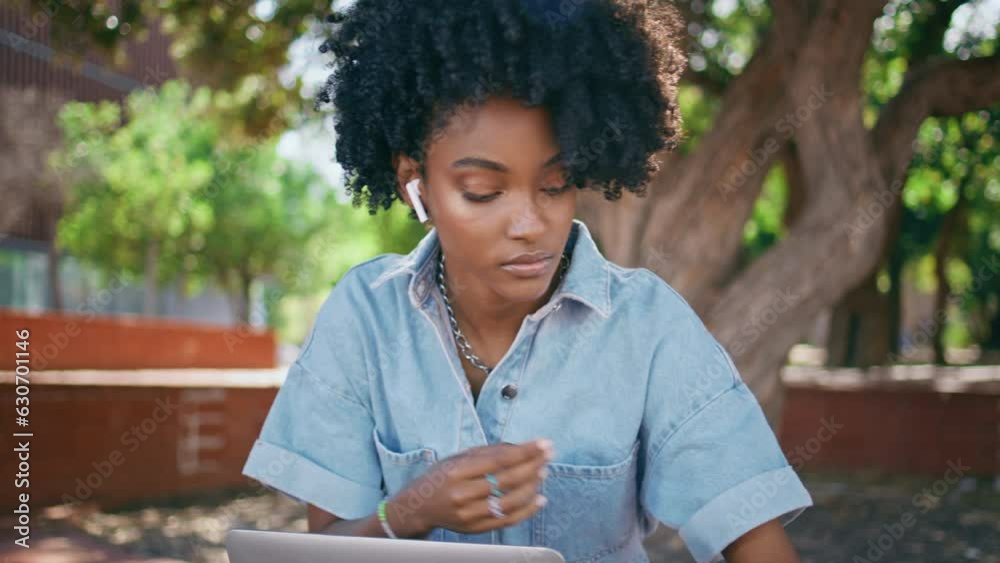 Teenager headphones turning music at smartphone sitting park with laptop closeup Teenager headphones turning music at smartphone sitting park with laptop closeup
