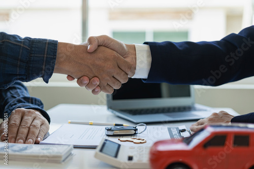 
image of men holding hands with a red car after signing the contract and paying successfully The car dealer or sales manager offers to sell the car and explains the terms of the car contract and insu photo