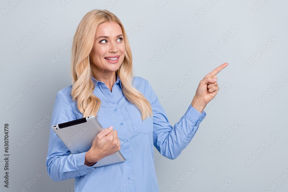 Portrait of elegant attorney lady hold tablet look direct finger empty space ad information isolated on grey color background Portrait of elegant attorney lady hold tablet look direct finger empty space ad information isolated on grey color background