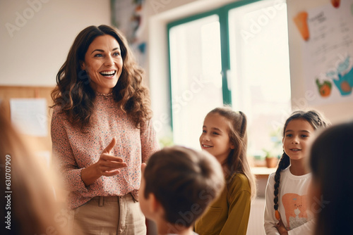 Portrait of smiling teacher in a class at elementary school looking at camera with learning students on background photo