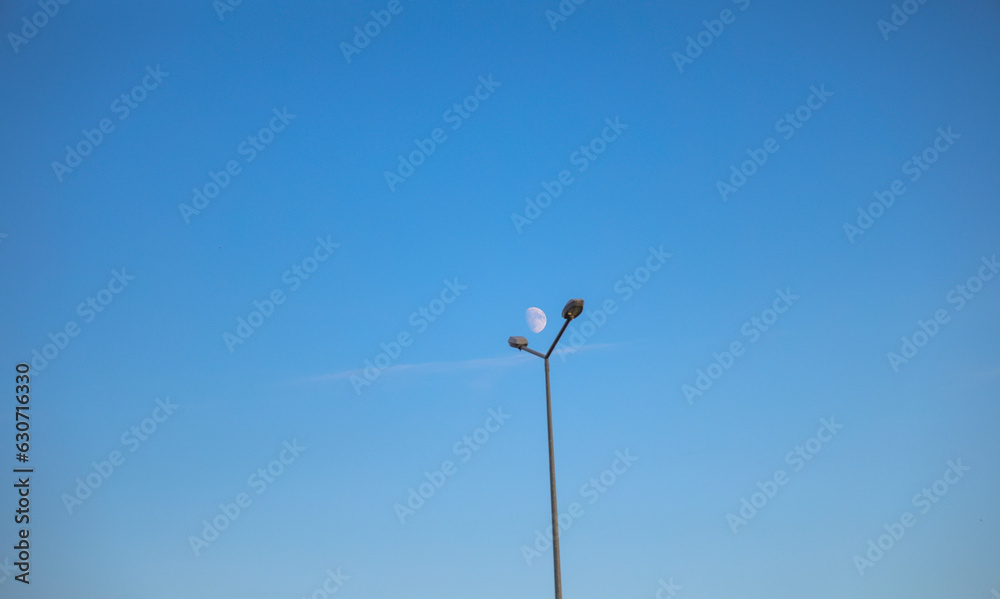 moon in blue sky and a street lamp post moon in blue sky and a street lamp post