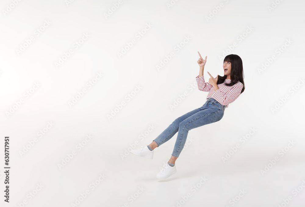 Young beautiful asian girl floating in mid-air relaxing and hand pointing finger to copy space with smile face and happy isolated on white background.