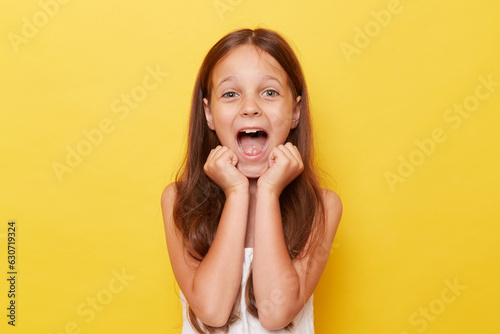 Canvastavla Overjoyed extremely happy little girl with ponytails standing isolated over yellow background screamign with clecnhed fits rejoicing her dream comes true