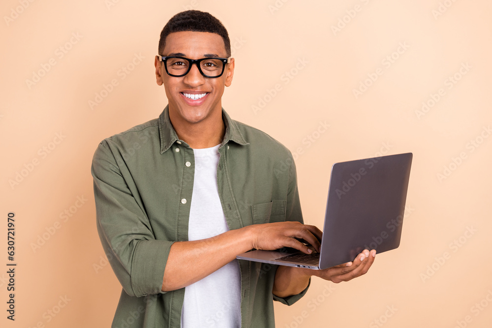 Photo of cheerful successful company representative toothy smile hold use netbook isolated on beige color background Photo of cheerful successful company representative toothy smile hold use netbook isolated on beige color background
