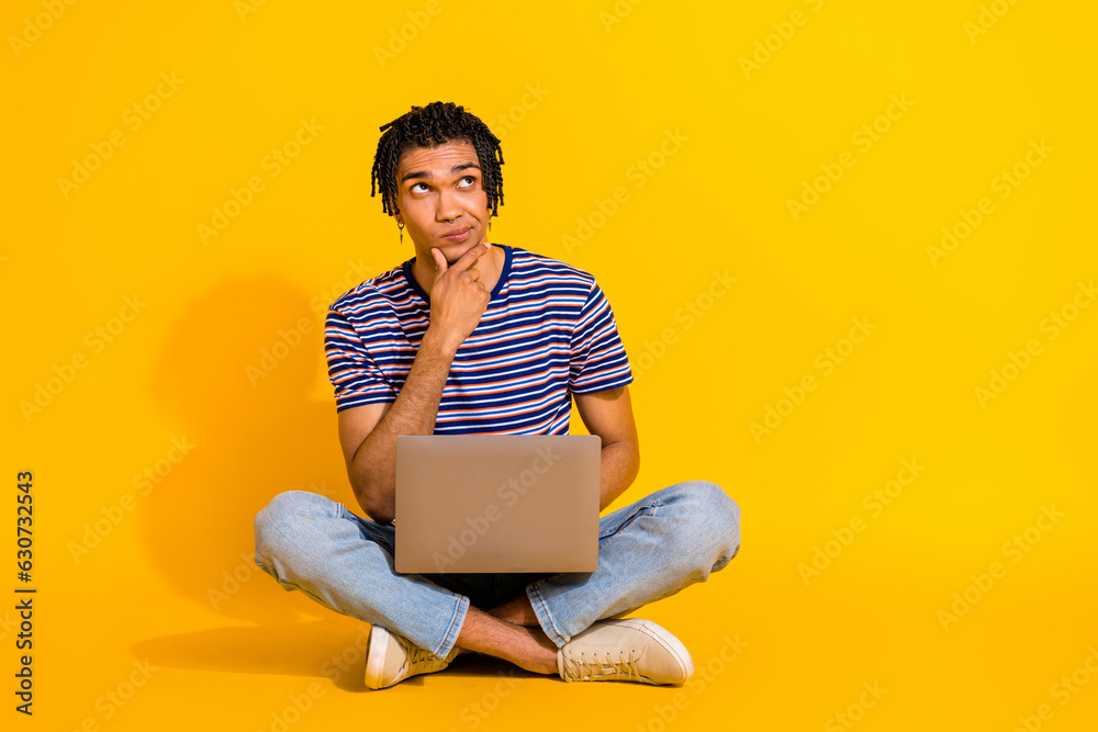 Full size photo of thoughtful minded ponder pensive man sit with laptop hand on chin look empty space isolated on yellow color background Full size photo of thoughtful minded ponder pensive man sit with laptop hand on chin look empty space isolated on yellow color background