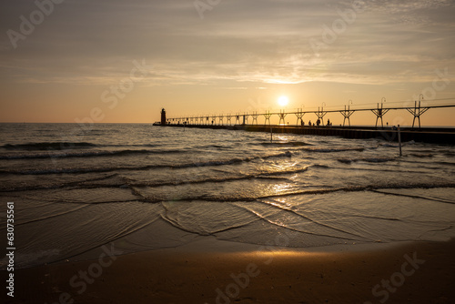sunset at the beach with a breakwater with a lighthouse