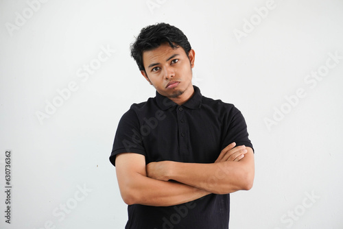 young Asian man in casual black polo t shirt with arm crossed tired of a repetitive task looking at camera studio shot isolated on white background