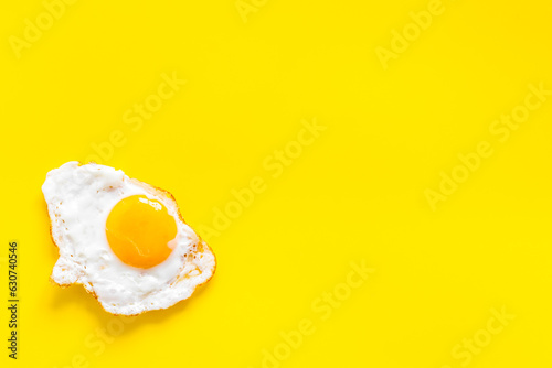 Fried egg close up on yellow background, top view. Breakfast concept